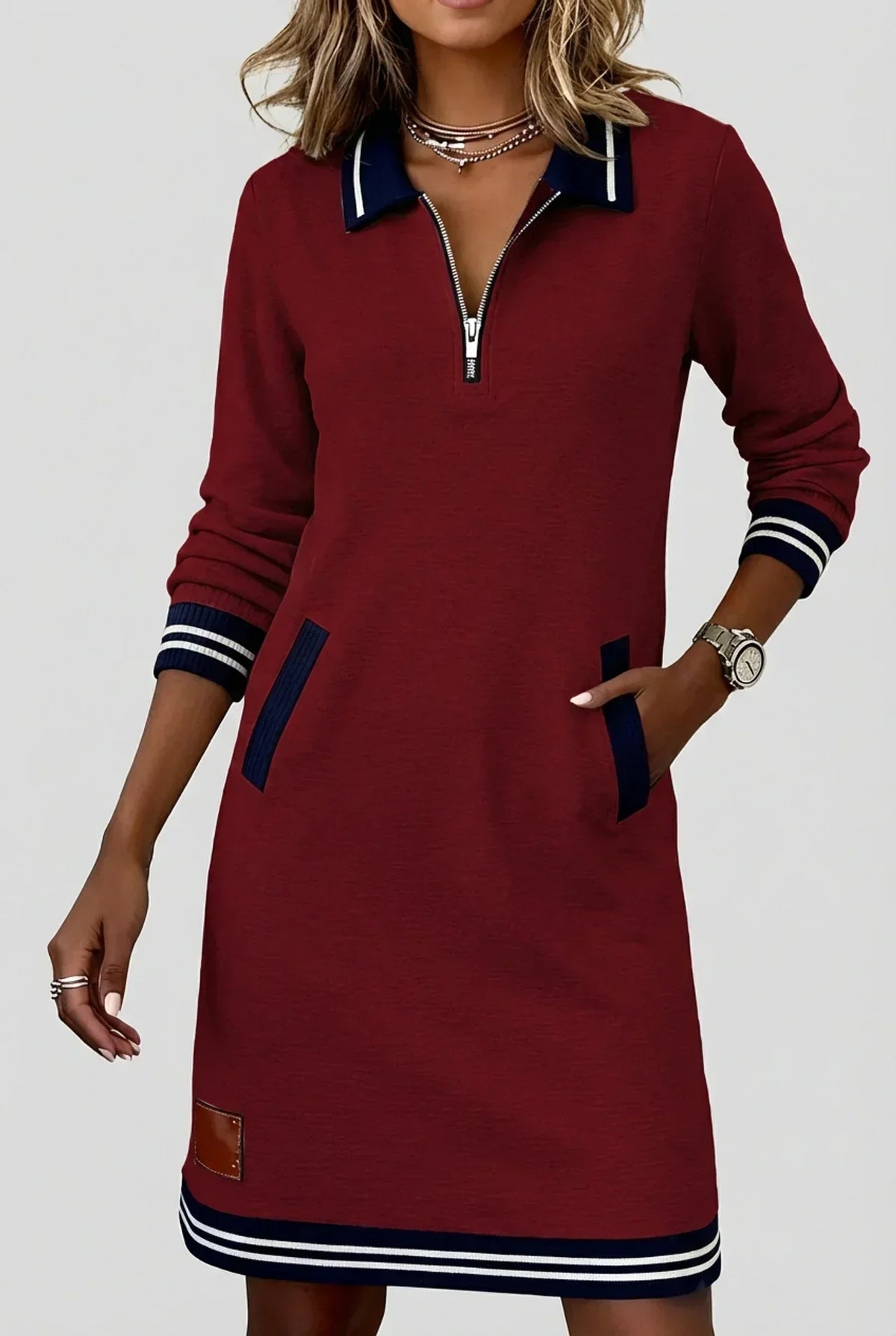 Model in the burgundy red dress with contrasting navy striped collar, cuffs and hem, one hand in a pocket. 5
