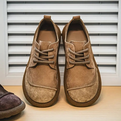 Pair of tan suede lace-up shoes with wide rounded toe caps and thick crepe-style soles, standing in front of white shutters. 1