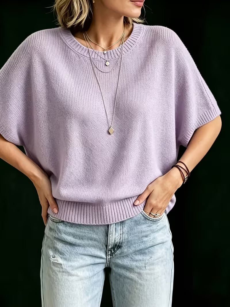 Lilac knit top worn with hands on hips, showing the cropped batwing silhouette and ribbed hem sitting at the waist. 11