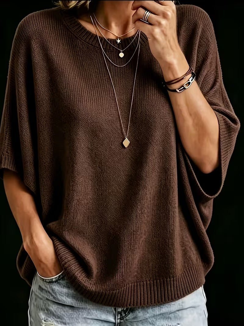 Close-up of the dark brown knit batwing top with layered necklaces, one hand raised to the chin. 17