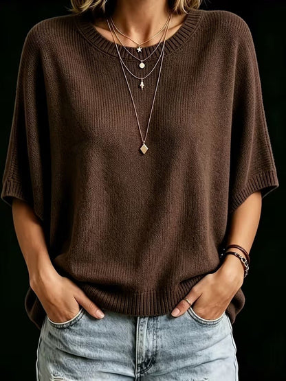 Dark brown knit top worn with both hands in the pockets of light jeans, showing the relaxed batwing fit. 18