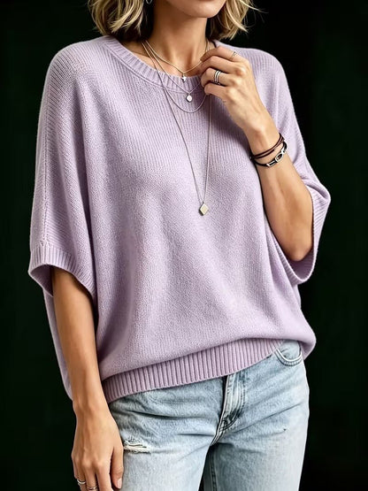 Lilac knit top worn by a model with light jeans, showing the loose batwing sleeves and ribbed round neckline. 8