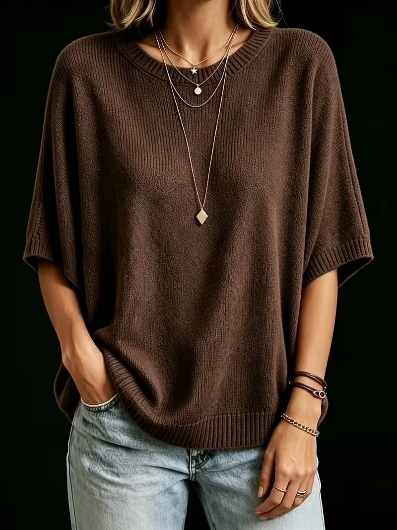 Dark brown knit top worn with one hand in a jeans pocket, showing the ribbed round neck and ribbed hem. 19