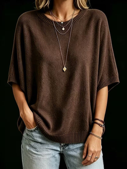 Dark brown knit top worn with one hand in a jeans pocket, showing the ribbed round neck and ribbed hem. 19