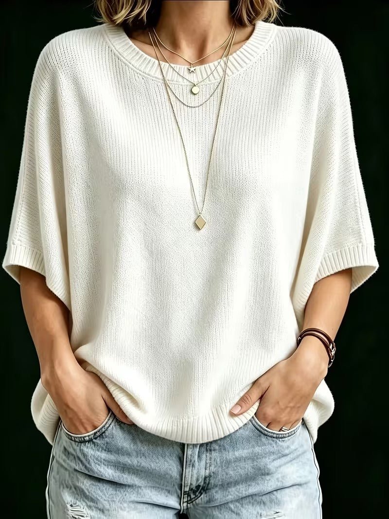 Front view of the cream knit top on a model, hands in jeans pockets, layered necklaces, ribbed neckline and sleeve cuffs. 23