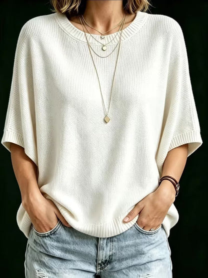 Front view of the cream knit top on a model, hands in jeans pockets, layered necklaces, ribbed neckline and sleeve cuffs. 23