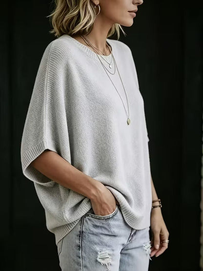 Side view of the light grey knit top on a model, showing the wide batwing sleeve and ribbed trim. 2