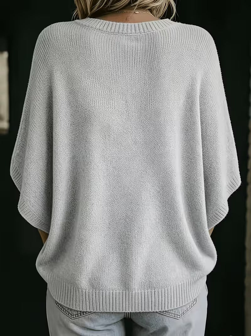 Back view of the light grey knit top, showing the ribbed round neckline, loose batwing sleeves and ribbed hem. 3