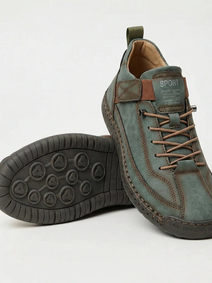 Green-grey trainers with brown laces and strap and a dark sole, one shoe showing the tread 16