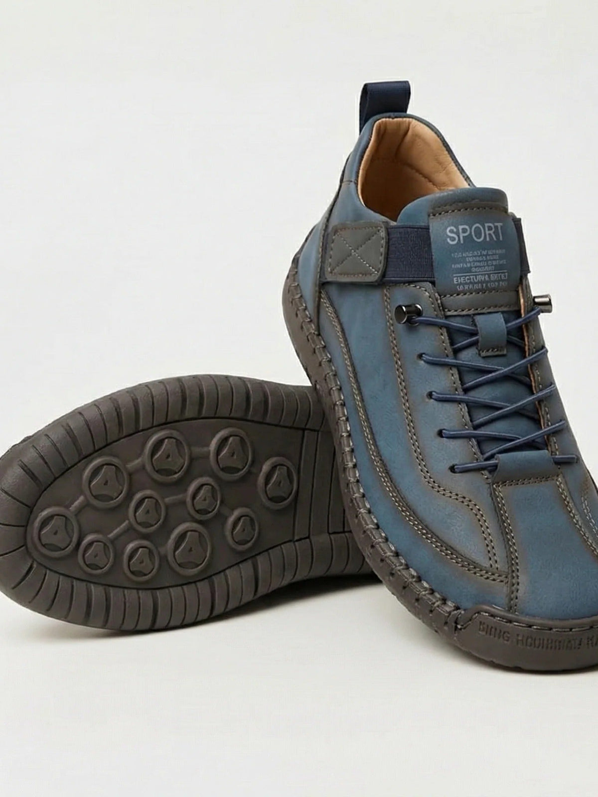 Blue-grey trainers with navy laces and a dark grey sole, one shoe resting on the other 8