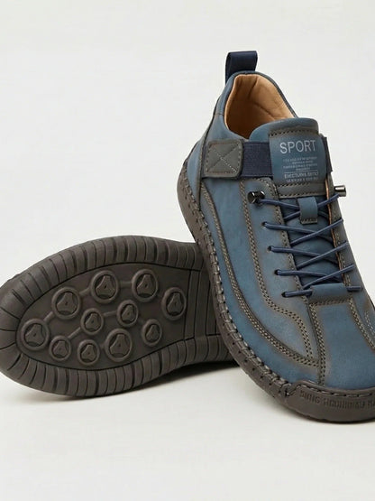 Blue-grey trainers with navy laces and a dark grey sole, one shoe resting on the other 8
