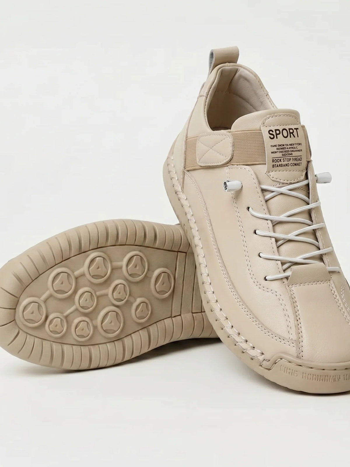 Cream trainers with white elastic laces and a matching sole, one shoe showing the tread pattern 12