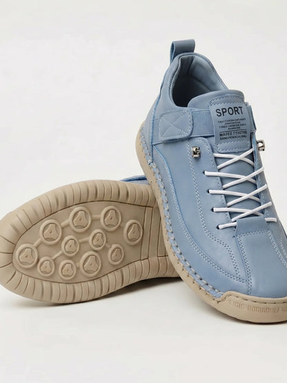 Light blue trainers with white laces and a beige sole, one shoe showing the studded tread 19