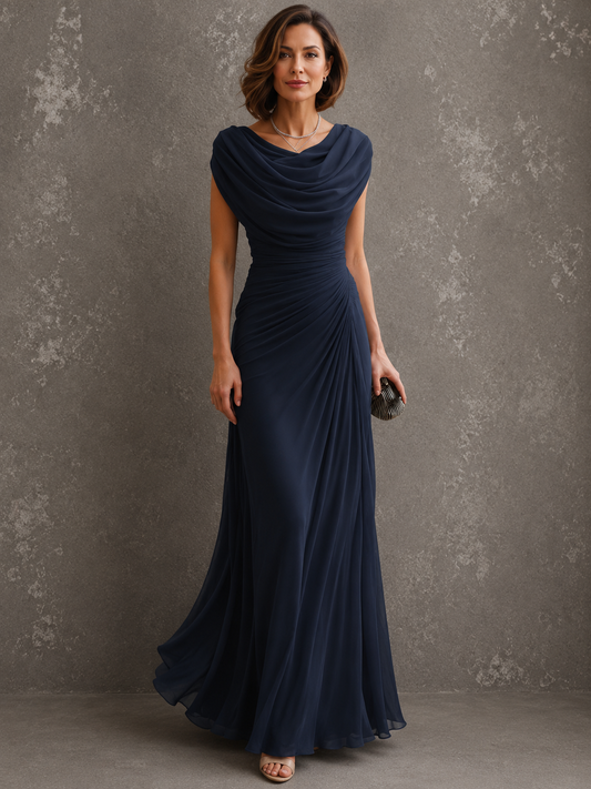 Model standing in the navy version of the dress, showing the draped cowl neckline, side-ruched bodice and long flowing skirt. 2
