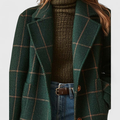 Close-up of the notched lapels and brown buttons on the green check coat, worn over a roll-neck jumper. 3