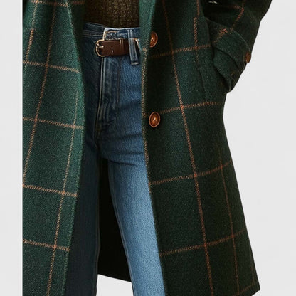 Close-up of the coat's front fastening with two brown buttons and a flap pocket, worn open over jeans. 5