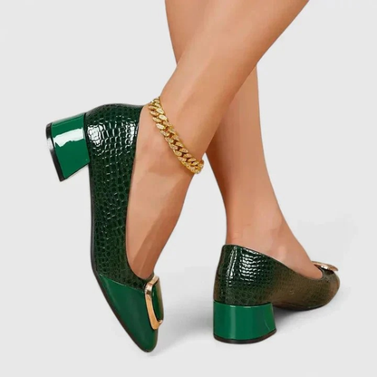 Dark green croc-effect block-heel loafers worn by a model, with glossy patent heel and gold-toned toe ornament. 6