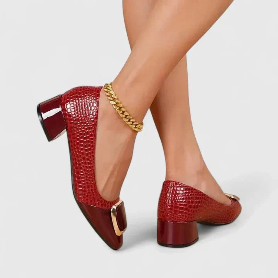 Red croc-effect block-heel loafers worn by a model with a gold ankle chain, showing the glossy heel and gold trim. 5