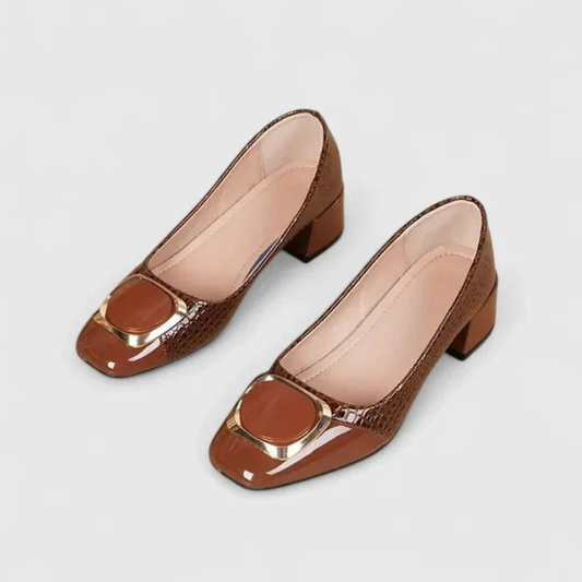 Pair of brown block-heeled loafers with croc-effect panels, patent toe caps and gold-edged ornaments, seen from above on a plain background. 1