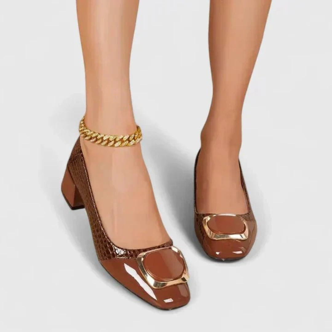 Front view of a model wearing the brown croc-effect block-heel loafers with a gold-toned ankle chain. 2