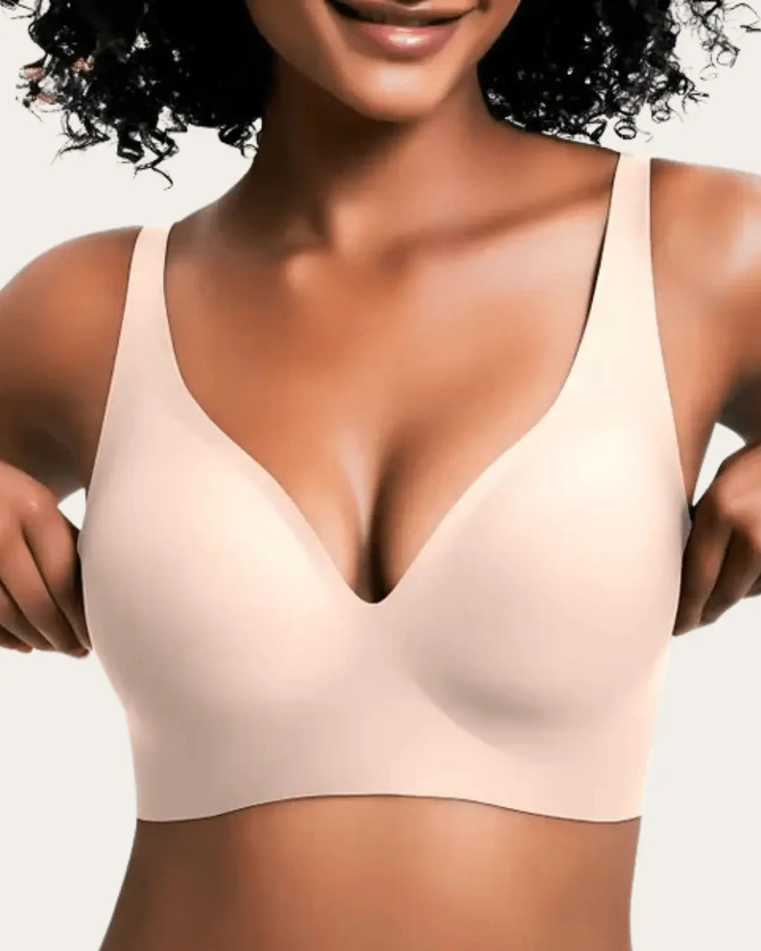 Front view of the wireless bra in a pale blush nude shade, worn by a smiling model. 7
