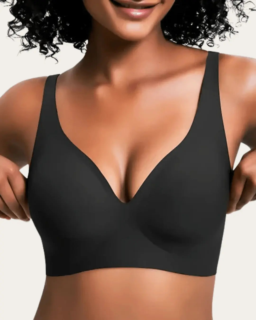 Front view of the seamless wireless bra in plain black, worn by a smiling model with curly hair. 3