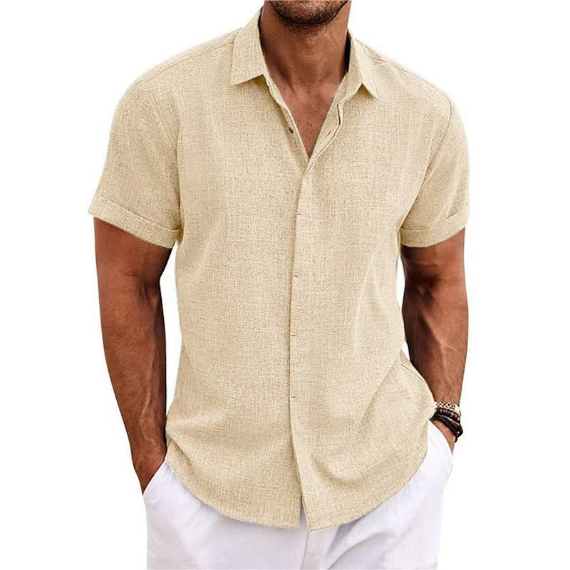 Cream textured short-sleeved shirt with a collar and rolled cuffs, worn by a model with white trousers. 11