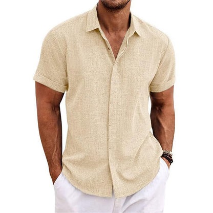 Cream textured short-sleeved shirt with a collar and rolled cuffs, worn by a model with white trousers. 11