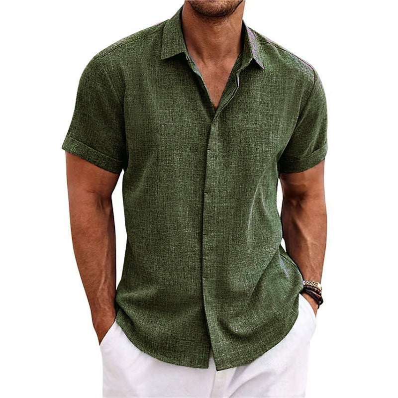 Olive green textured short-sleeved shirt with a collar and rolled cuffs, worn by a model with white trousers. 12