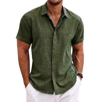 Olive green textured short-sleeved shirt with a collar and rolled cuffs, worn by a model with white trousers. 12