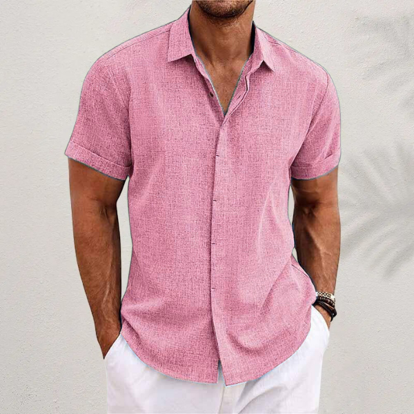 Pink textured short-sleeved shirt with cuffed sleeves, worn by a model with white trousers against a pale wall. 9