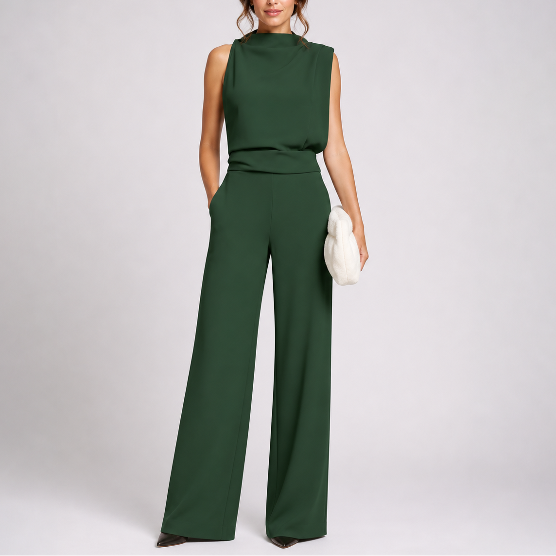 Model wears the sleeveless jumpsuit in dark green with pointed black shoes, holding a fluffy cream clutch 1