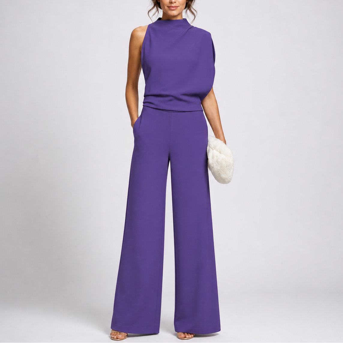 Model wears the jumpsuit in purple with an asymmetric draped top, strappy sandals and a fluffy cream clutch 3