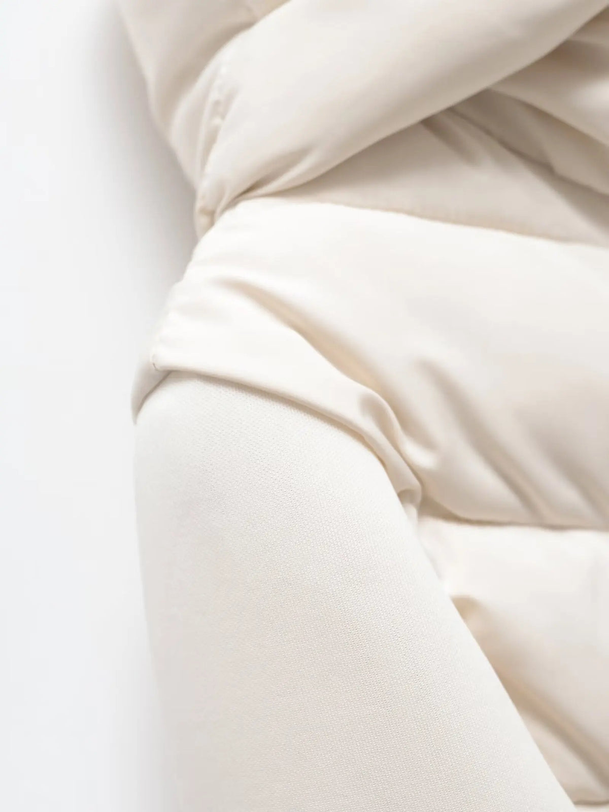 Close-up of the cream jacket's shoulder, where the smooth padded body meets the soft fabric sleeve. 4