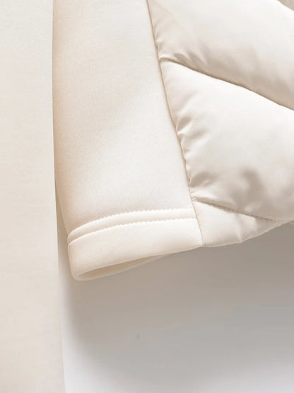 Detail of the cream jacket's cuff and the quilted panel beside it, laid flat on a white background. 6