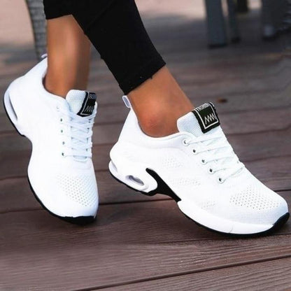 White breathable mesh trainers with black-trimmed heel tab and black sole edge, worn mid-step with black leggings. 3