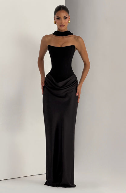 Black strapless dress styled with a fabric collar choker, model standing in a studio corner 26