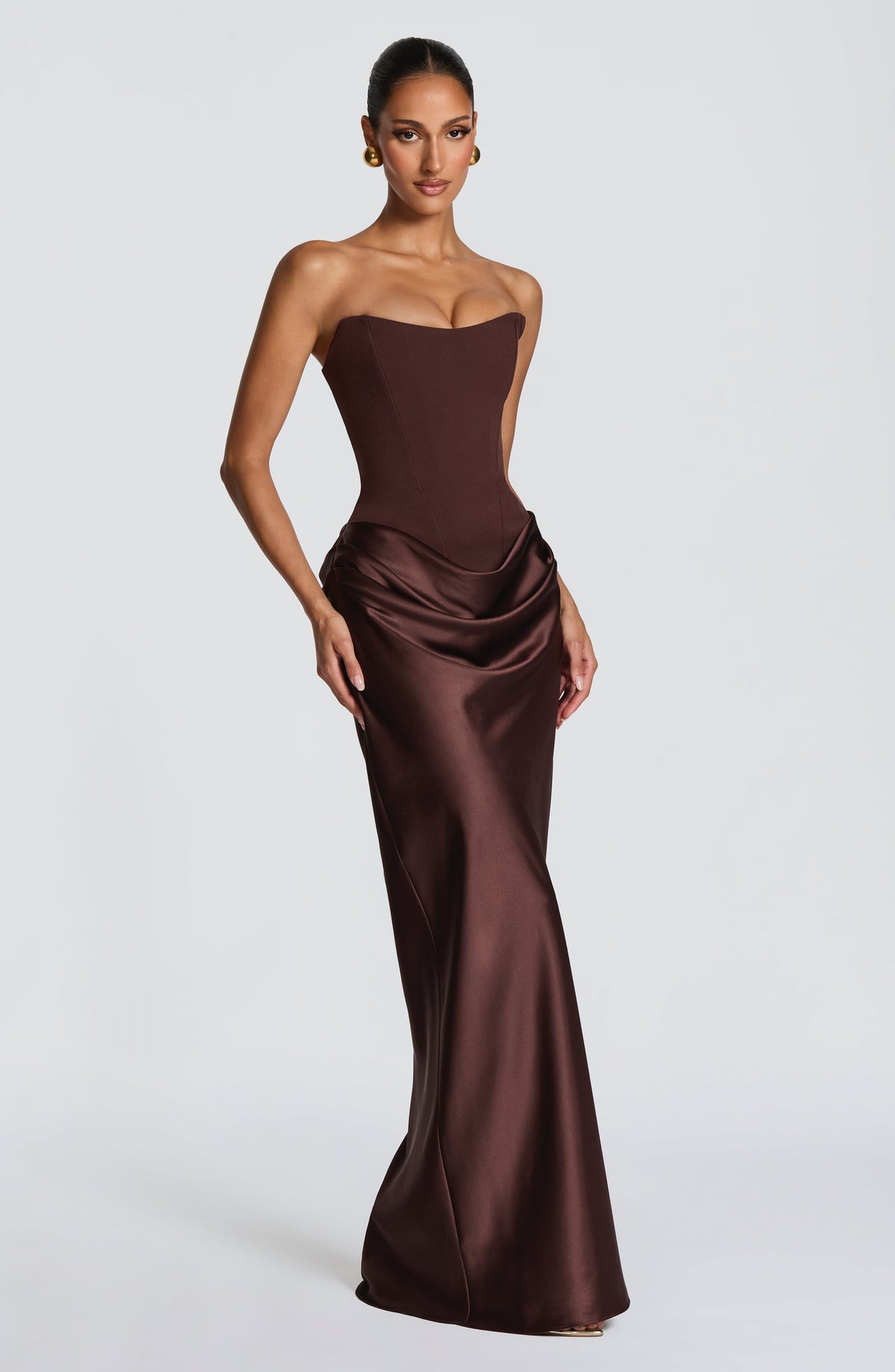 Three-quarter front view of the brown dress with the draped satin cowl skirt falling to the floor 3