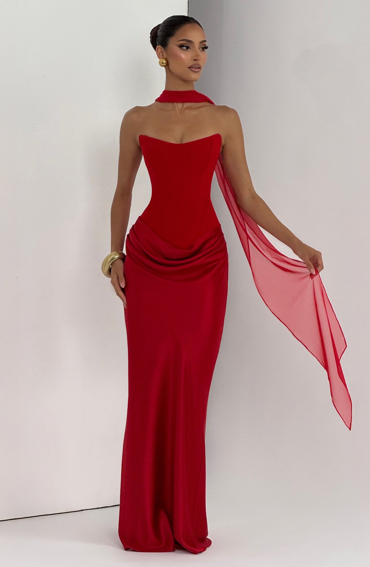 Red dress with a sheer scarf held out to one side, worn with a gold bangle 19