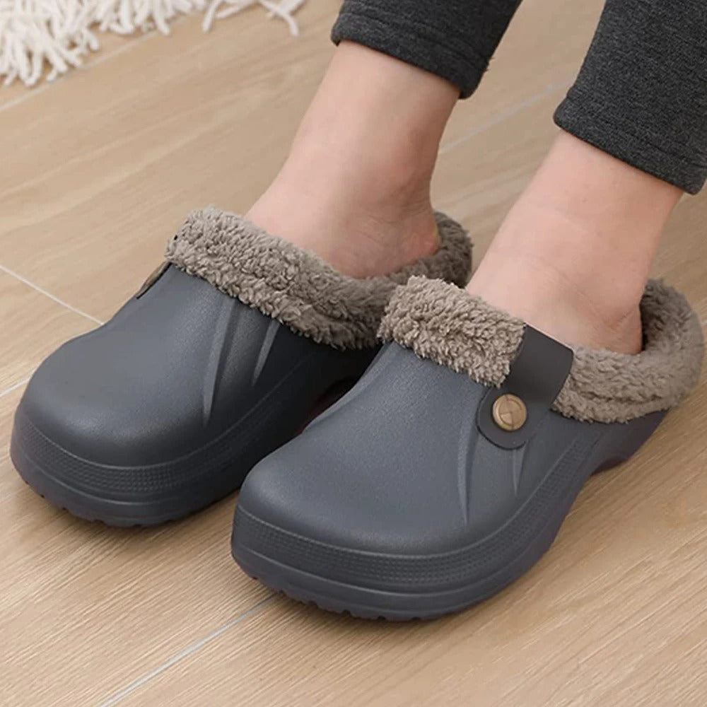 Close-up of feet in grey clogs with fleece lining and button straps on a wooden floor 8