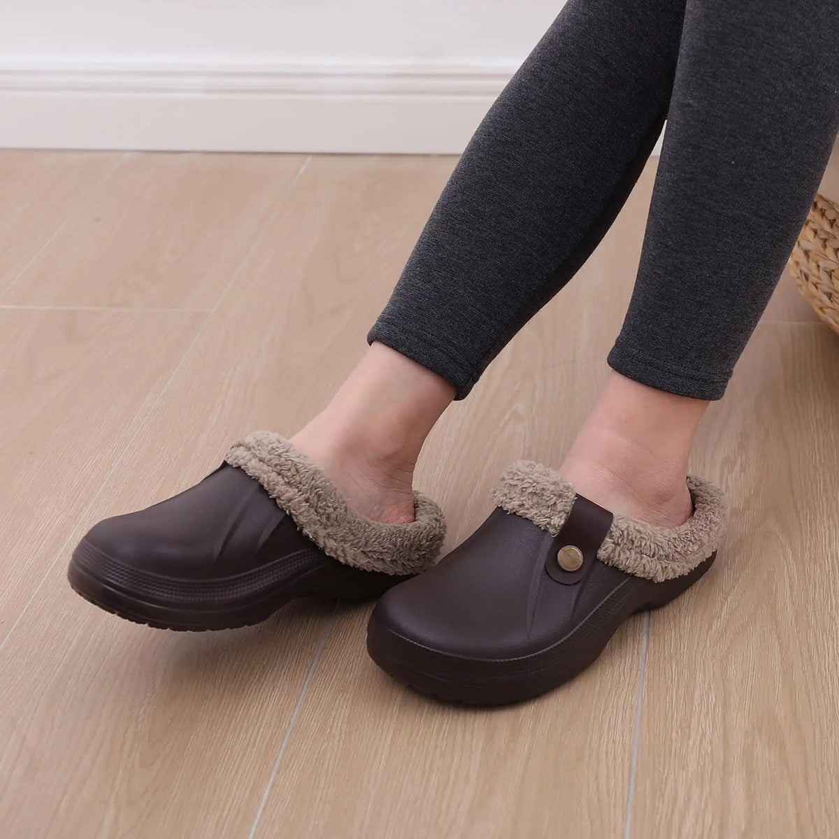 Person in grey leggings wearing brown fleece-lined clogs on a light wooden floor 7