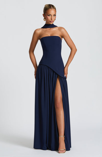 Model in the navy blue strapless dress with a neck scarf, gathered skirt and high thigh slit, with gold heels. 7