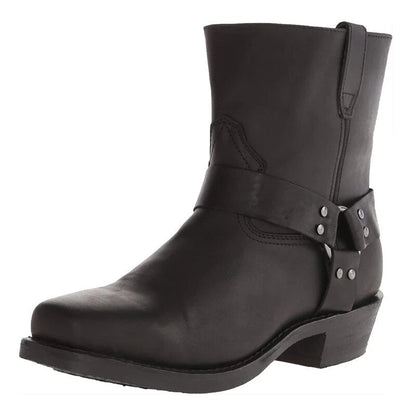 Black version of the leather harness boot at a three-quarter angle, with studded ring strap and block heel. 2