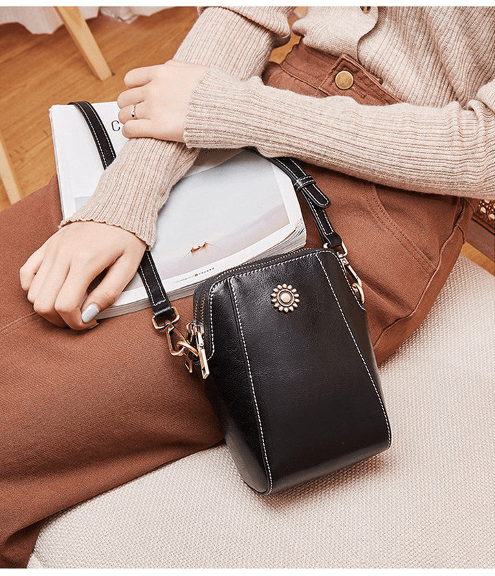 Black bag worn across the body by a seated woman in a knit jumper, resting on her lap 9