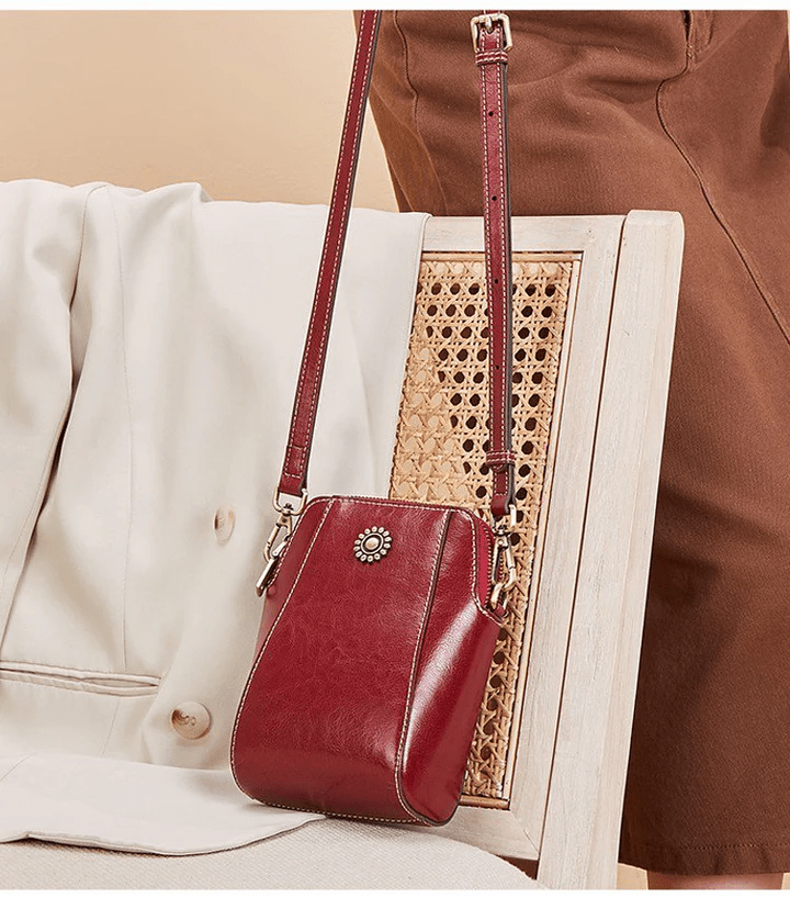 Burgundy bag hanging by its strap from a rattan-backed chair beside a cream jacket 5