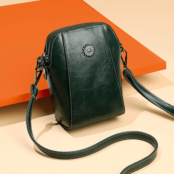 Dark green version at an angle against an orange panel, with its strap looped in front 8