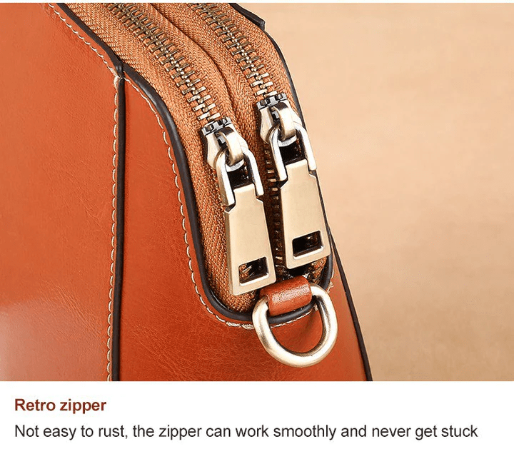 Close-up of the two antique-brass zip pullers and a metal ring on the tan bag 13