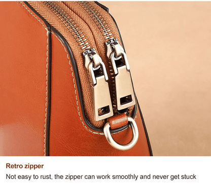 Close-up of the two antique-brass zip pullers and a metal ring on the tan bag 13