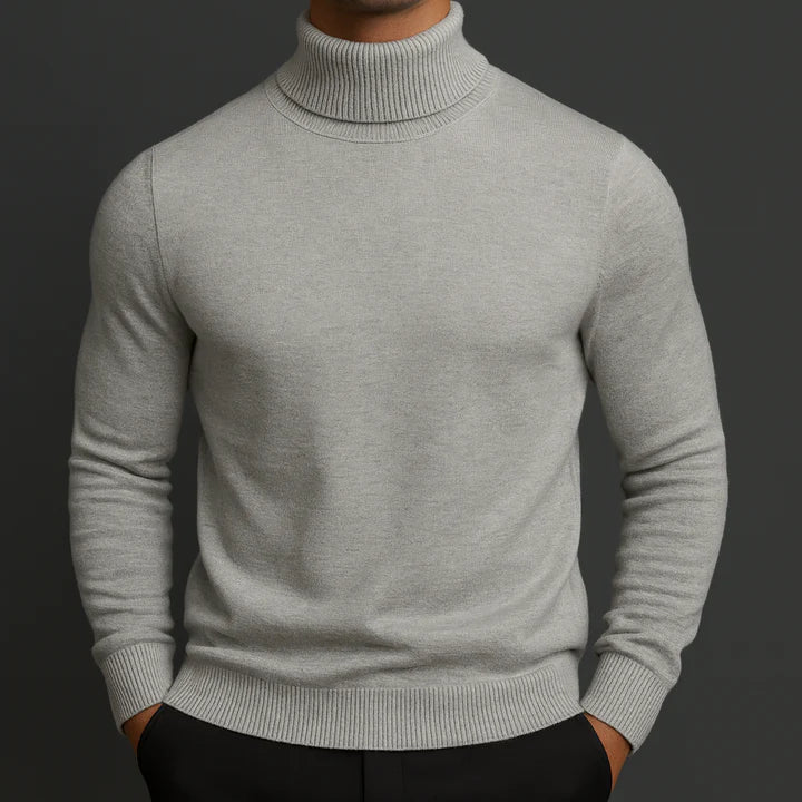 Model wearing the light grey turtleneck jumper with ribbed collar and cuffs, hands in black trousers 2
