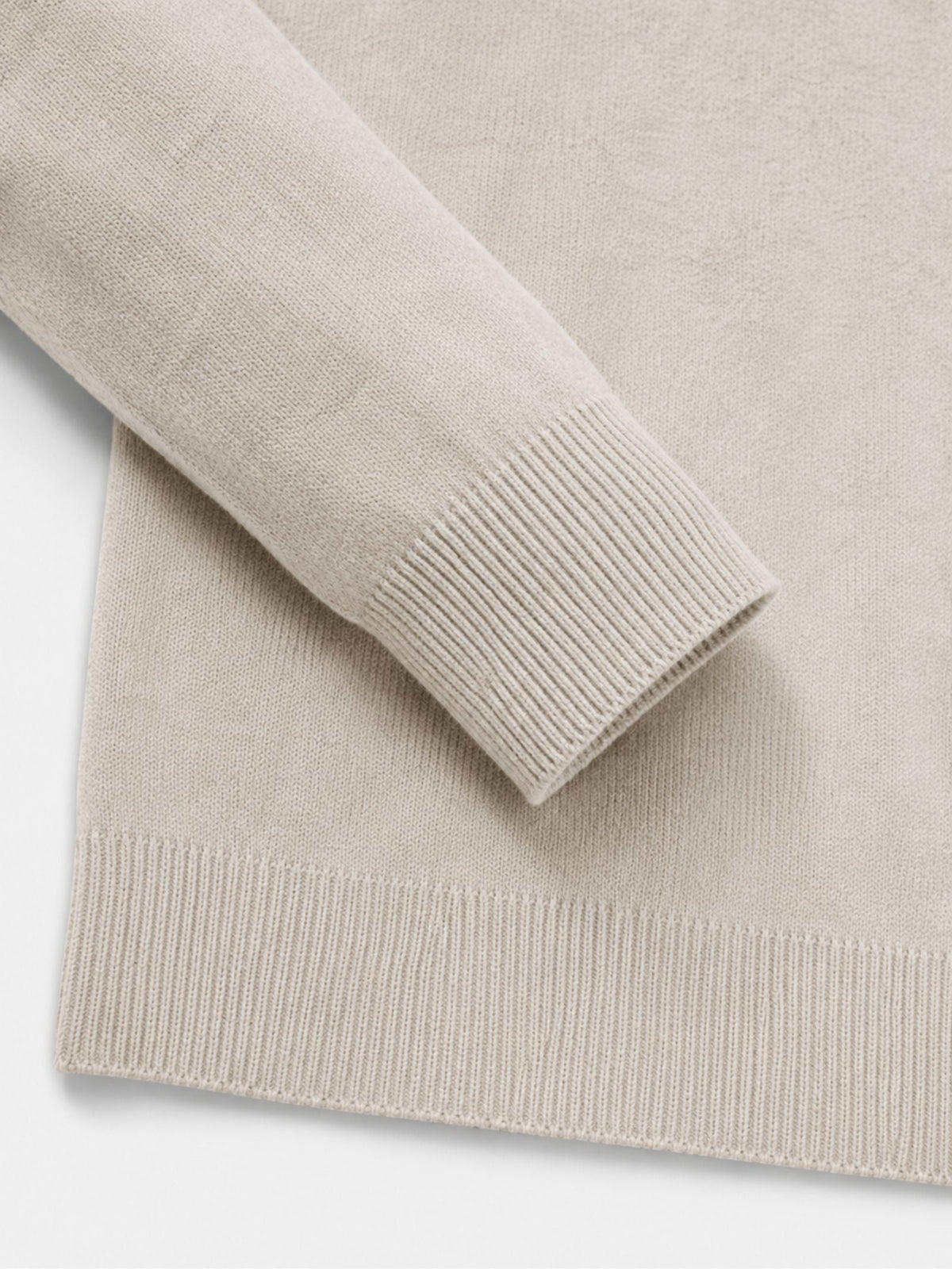 Detail of the cream jumper's ribbed cuff and hem, showing the fine knit texture of the sleeve and body. 15